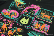 The top of the Stray Antics shirt design in a closeup photo. The cat is shown in a collage walking across a keyboard, falling, skulking over a set of TV monitors, scratching a mat, and looking back at its backpack as B-12 looks on.  Thumbnail